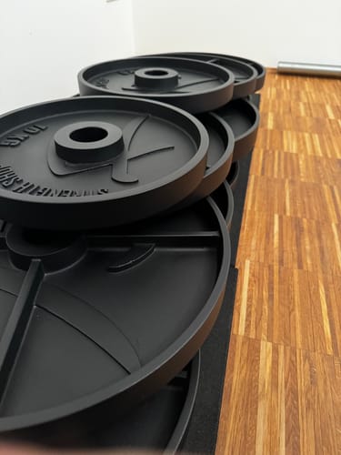 Customer's black Deep Dish Cast Iron Plates standing on edge in a clean row on a floor mat.