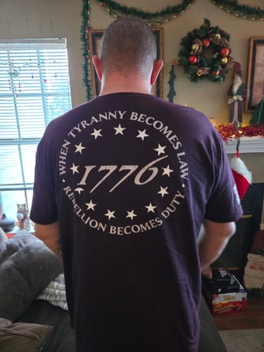 Reviewer from behind wearing the dark purple 'When Tyranny Becomes Law 1776' t-shirt.
