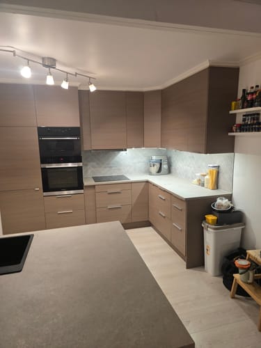 Anmelderens kjøkken med skapfronter dekket av Tuscan tan kontaktplast, sett fra siden.