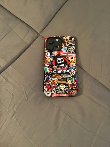 Customer's Chingon Stickered Tough Case for iPhone® shown on a gray, tufted comforter.