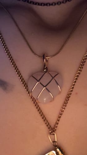 Close-up of a reviewer wearing the heart-shaped rose quartz necklace with gold wire wrapping.