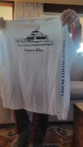 Reviewer holds a white long-sleeved shirt with custom boat art and incorrect 'Grady-White' text printed on the sleeve.