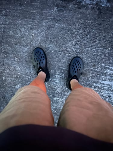 Customer's first-person view of their black Nike ReactX Rejuven8 Shoes on a paved surface.