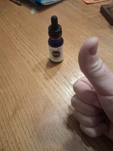 Reviewer gives a thumbs-up next to their bottle of Meraki Blu Methylene Blue on a wooden table.
