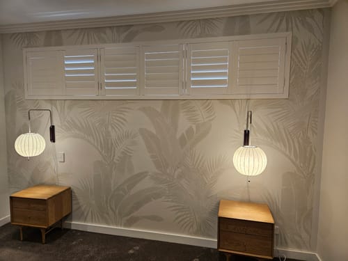 Customer's bedroom showing the Luxe Tropical in Neutral Wallpaper as an elegant feature wall behind two nightstands.
