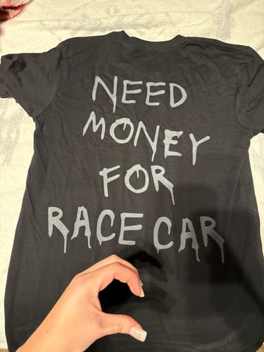 Reviewer showing the back of the black RACE CAR DREAMS TEE with 'NEED MONEY FOR RACE CAR' text.