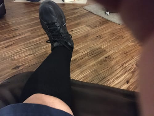Customer's leg propped up, wearing a black Performance Eucalyptus Compression Sock with a black sneaker.