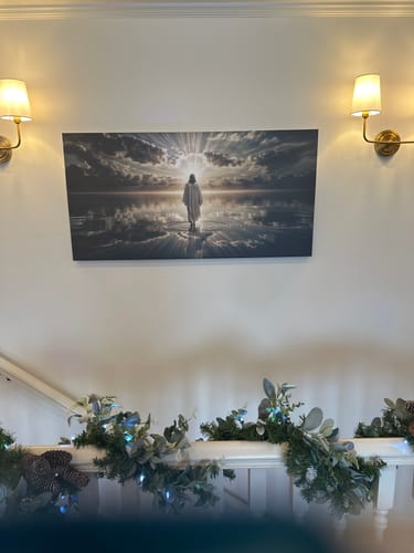 Customer's 'Walking on Water' canvas art displayed on a wall between two lit sconces.