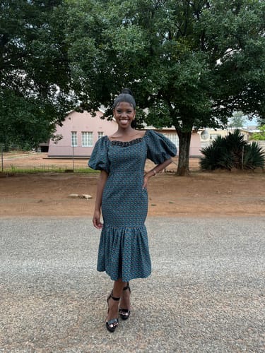 Reviewer standing outdoors wearing the green patterned Ankara midi dress with puffy sleeves.