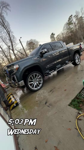 Reviewer's lifted dark gray GMC Sierra 1500 parked on a wet driveway after installing the 3" Front Leveling Lift Kit.