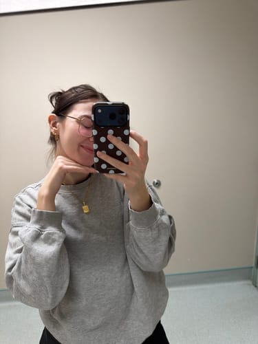 Reviewer taking a mirror selfie, showing the brown polka-dot Couture Mocha phone case.