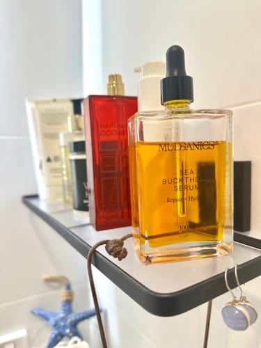 Customer's Sea Buckthorn Serum in a clear bottle with a black dropper, displayed on a bathroom shelf.