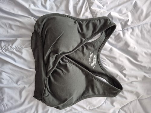 Reviewer's dark grey Lovemère Seamless Nursing Bra laid out on a white quilted bedspread.