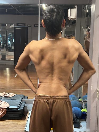Reviewer shows their defined back muscles in a gym after using Wellcore Creatine Monohydrate.