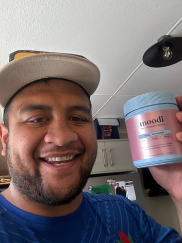 A smiling reviewer holding up their tub of Pink Lemonade.