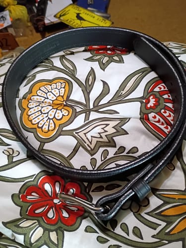 Customer's black Montana Bison Double Layer belt coiled on a floral surface, showing the sturdy buckle.