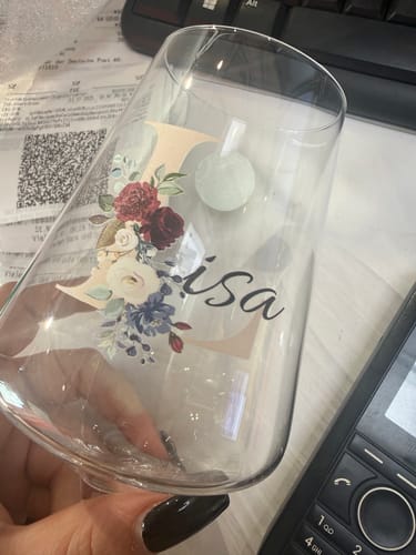 Ein Kunde hält das personalisierte Weinglas mit dem blumigen Initial 'L' und dem Namen 'Lisa' in der Hand.