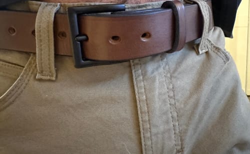 Close-up of a customer wearing the brown leather Everyday belt with a black buckle and tan pants.
