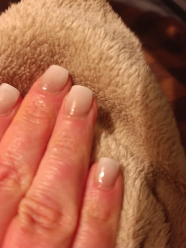 Nahaufnahme einer Kundenhand mit glänzenden 'Babyboomer Nude' UV-Gel-Nagelfolien.