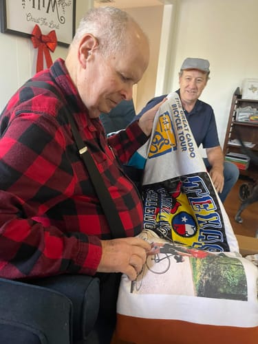 Customer sitting and admiring his new Premium T Shirt Quilt made from colorful bicycle-themed t-shirts and photos.