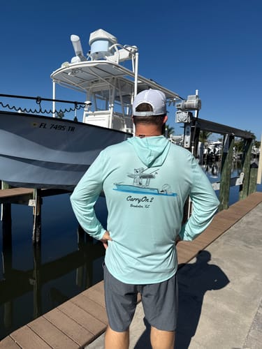 Customer wearing a light blue shirt featuring the Custom Digital Boat Artwork, standing next to the real boat.