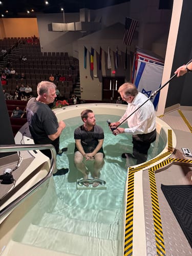 A reviewer wears the Nailed to the Cross necklace while being baptized in a church baptismal pool.