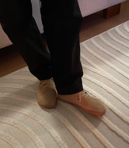 Asiakkaan jalassa vaaleanruskeat Vaistoa Iloa -paljasjalkatennarit yhdistettynä mustiin housuihin.