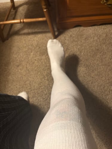 Customer's leg wearing a white, ribbed Performance Eucalyptus Compression Sock indoors.