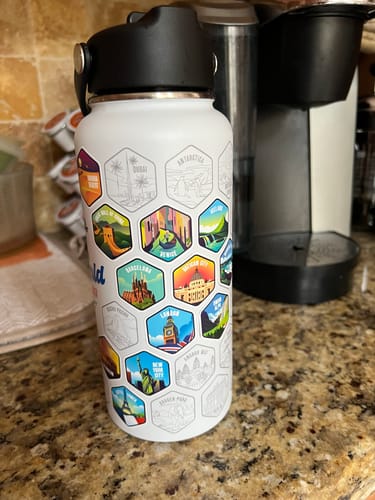 Customer's World Explorer Water Bottle with several colorful destination stickers applied and many blank outlines for future travels.