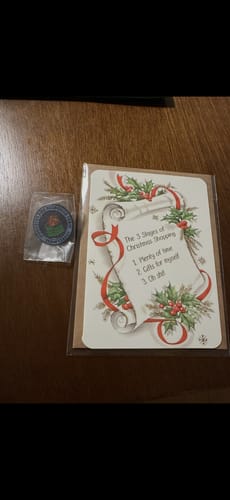 Reviewer's Dumpster Fire Response Team Leader Pin in its packaging, shown next to a greeting card on a wooden table.