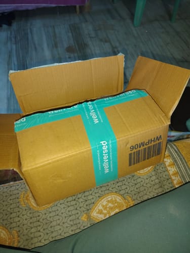 Reviewer shows the product box for Wellcore Creatine Monohydrate inside an open shipping carton.