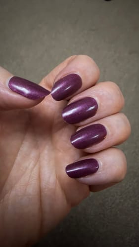 Customer's hand showing a glossy manicure with shimmering, deep purple Mulled Wine Shimmer nail gels.