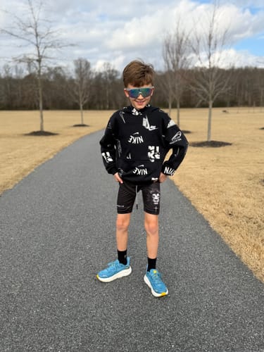 Customer wearing the black Joshua 1:9 'Lion' Youth Performance Shorts on a paved outdoor path.