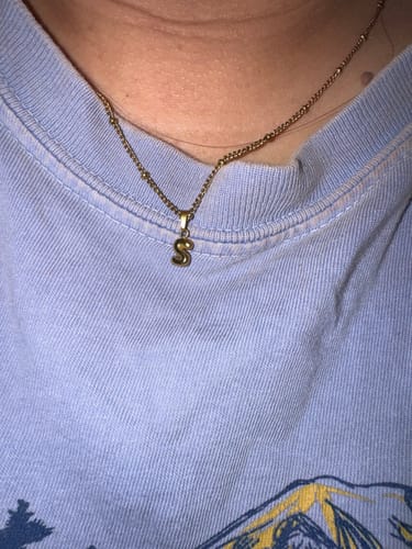 Close-up of a customer wearing the gold Tiny bubble initial necklace with an 'S' charm.