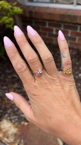 Customer's hand wearing the dainty Leesha Birthstone Ring with two different colored stones.