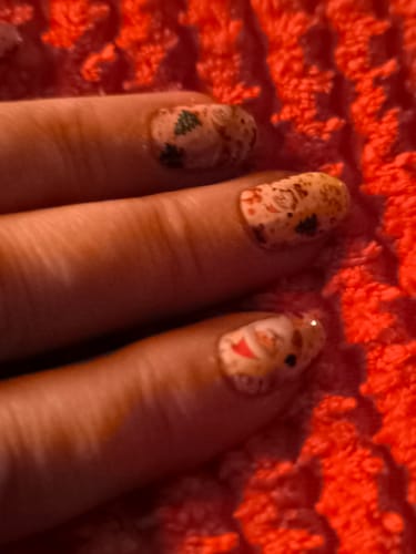 Kundenrezension: Nahaufnahme der Nägel einer Person, die die festlichen „Ho Ho Ho, Honey!“-Nagelfolien trägt.