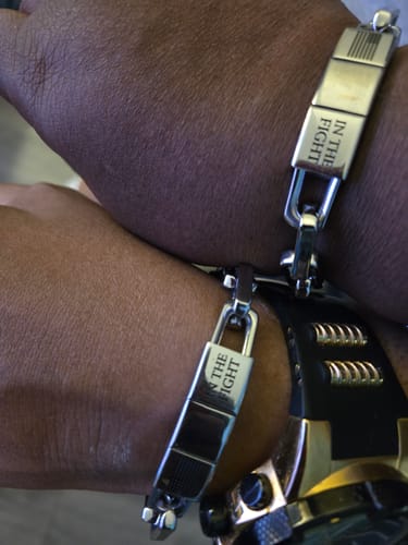 Customer's close-up of two people wearing matching 'In The Fight-Never Surrender Bracelets'.