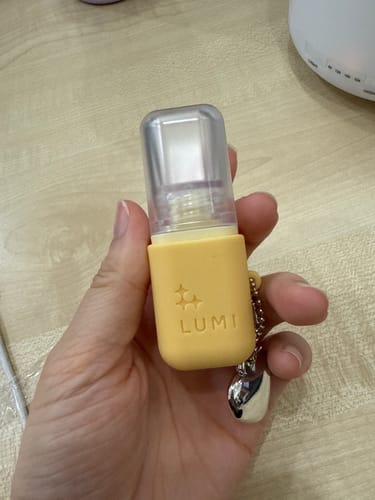 Customer holding the Deep Hydration Lip Oil in its cute yellow case with an attached heart charm.
