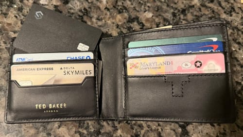 Customer showing their black SPOTMINDERS Tracking Card PRO inside an open bifold wallet with other cards.