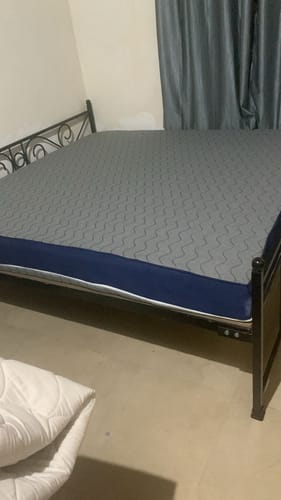 Customer's Flo Mattress Ergo with a grey patterned top and blue sides, placed on a black metal bed frame.