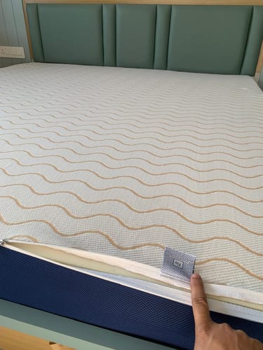 Close-up: Customer pointing at the tag and zipper on the Flo Mattress Ortho's patterned cover.