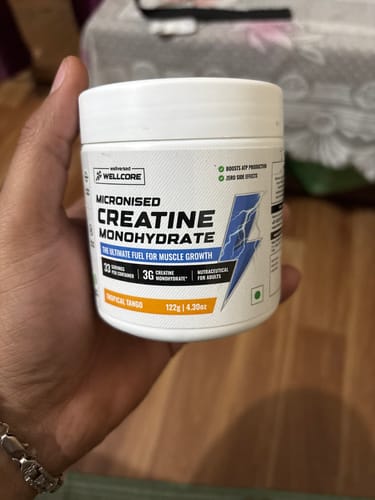 Customer holding a white tub of Wellcore Micronised Creatine Monohydrate in the Tropical Tango flavor.