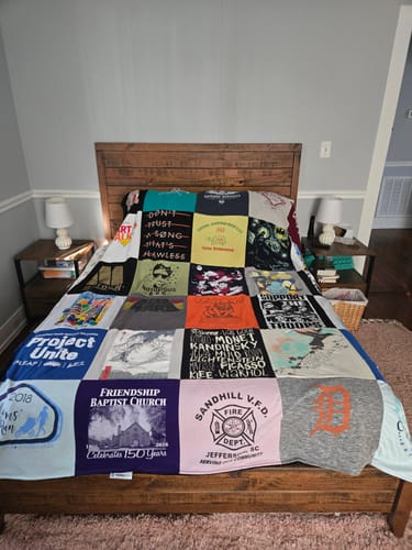 Customer's colorful T-Shirt Quilt made from various shirts spread across a bed in a bedroom.