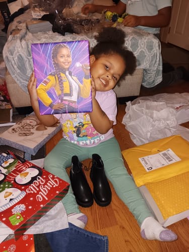 Reviewer's smiling child holding up her personalized K-Pop Queen The Magic Beats portrait.