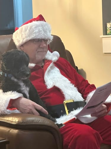 Customer in a Santa costume with a puppy, reading a script from the Christmas Murder Mystery game.