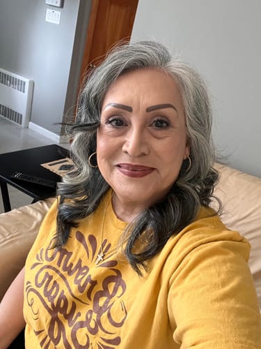 A smiling reviewer wearing the gold Brown Sugar Tee with a brown graphic print.