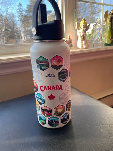 Reviewer's white Canada Bottle showing the colorful stickers they've added for places they have visited.