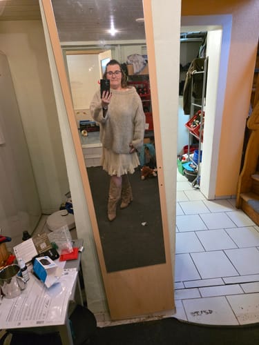 Kundin macht eine Spiegelaufnahme und trägt die Cowboy Stiefel Sierra zu einem beigen Pullover und Rock.