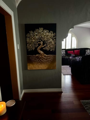 Reviewer's Tree of Life Wall Art with golden details hanging on a gray wall in a hallway.