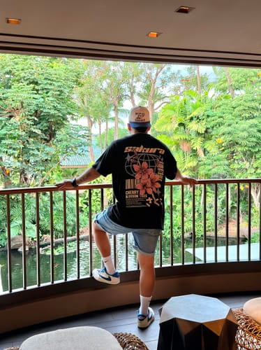 Customer on a balcony wearing the black Sakura Style T-Shirt, showing the large back graphic.